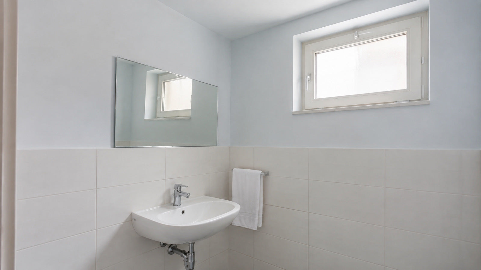 Bagno con fascia alta tinteggiata in azzurro chiaro sopra le piastrelle
