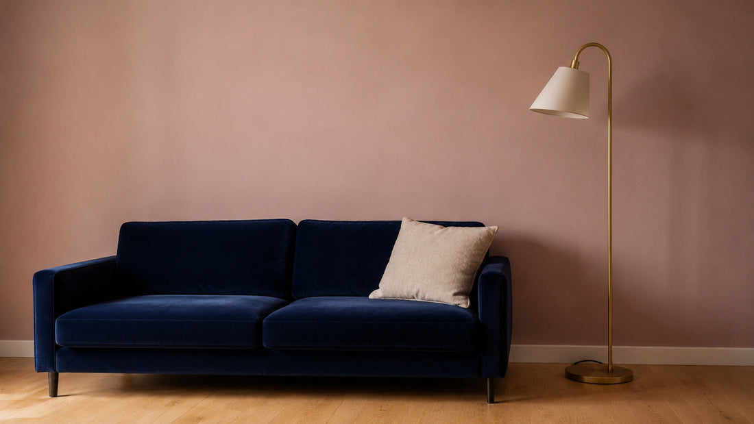 Parete in rosa cipria polveroso con divano blu e lampada da terra in ottone